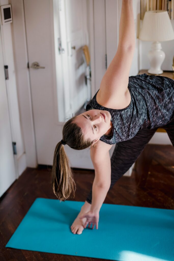 A woman practicing yoga indoors, stretching on a blue mat for relaxation and fitness.